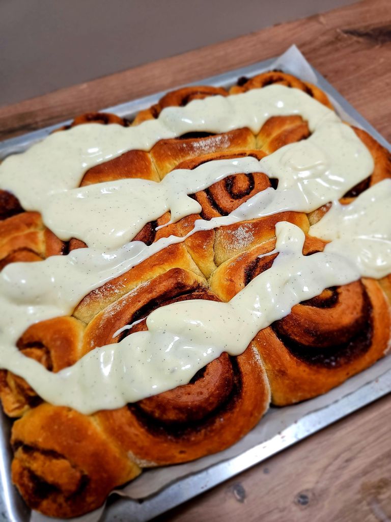 Cream Cheese Honey Glaze being drizzled over cinnamon roll
